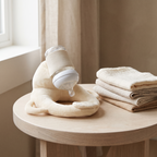 Cradlely bottle holder on a pale wood table beside folded muslin