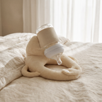 Cradlely bottle holder on cream linen bedding with a bottle in place