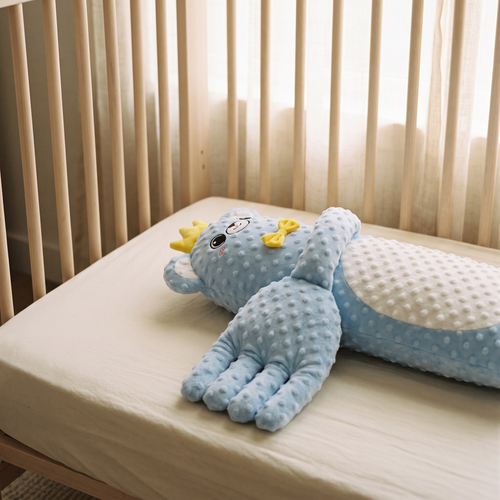Lull baby patter lying across a crib mattress with a cream sheet